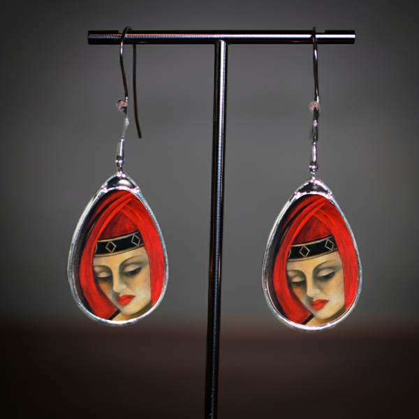Teardrop-shaped earrings with a face design on a white background