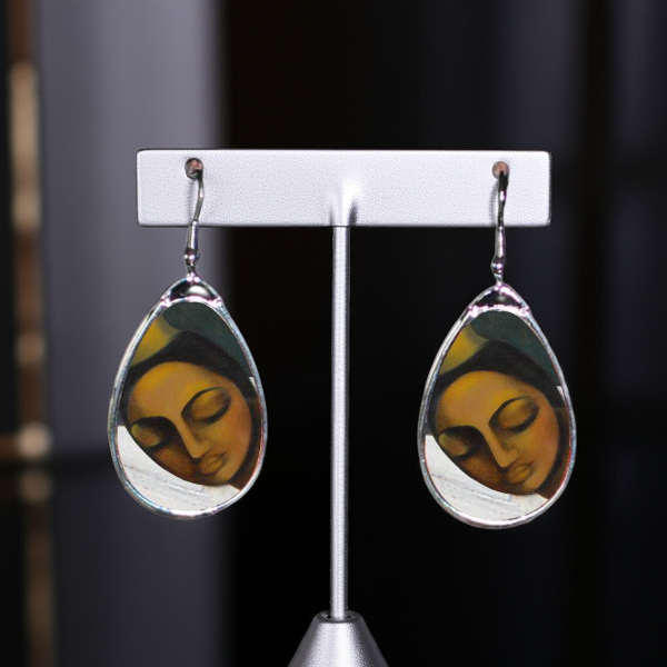 Teardrop-shaped earrings with a face design on a white background
